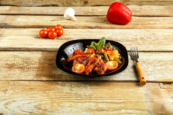 用番茄酱烤鸡翅，配上米饭和蔬菜，放在靠近蔬菜的木制桌子上装饰 — 图库照片