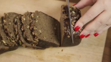 Bir kadın eli, tahtadan bir bıçakla kepekli çavdar ekmeğini keser..