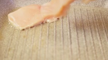 Izgara maşaları tavada tavuklu filetoya konur..