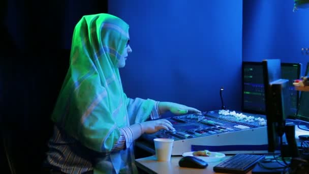 Uma mulher muçulmana em hijab e óculos, um designer de iluminação programa a luz para um show . — Vídeo de Stock