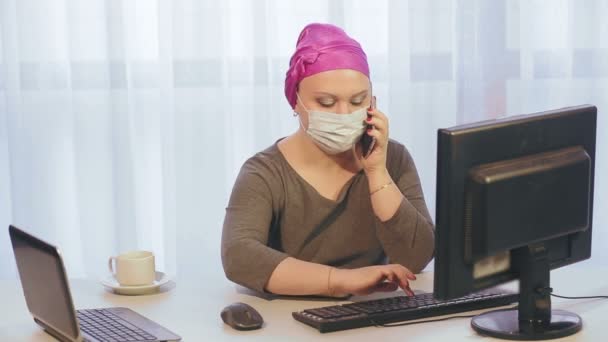 Una mujer judía en un tocado en el trabajo durante el período de cuarentena, el coronavirus habla por teléfono y trabaja en la computadora . — Vídeos de Stock