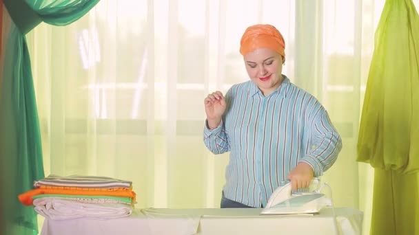 Еврейская домохозяйка гладит белое белье на гладильной доске дома — стоковое видео