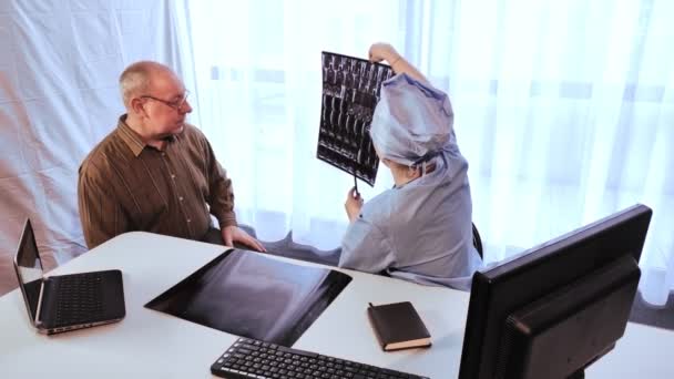 Une femme médecin dit à un homme un diagnostic basé sur les résultats de l'imagerie par résonance magnétique de la colonne vertébrale . — Video