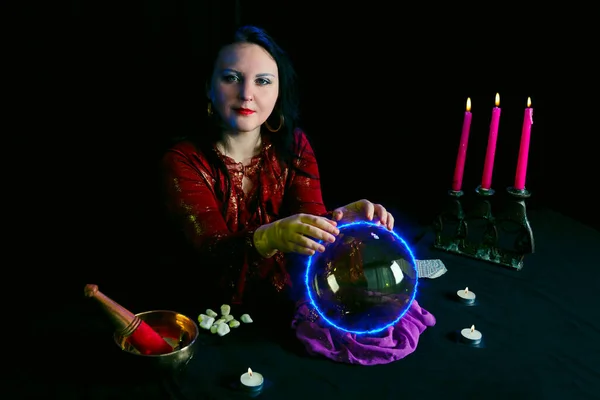 A young clairvoyant and fortuneteller divines over a mirror ball in a magic salon on a black background. — Stock Photo, Image