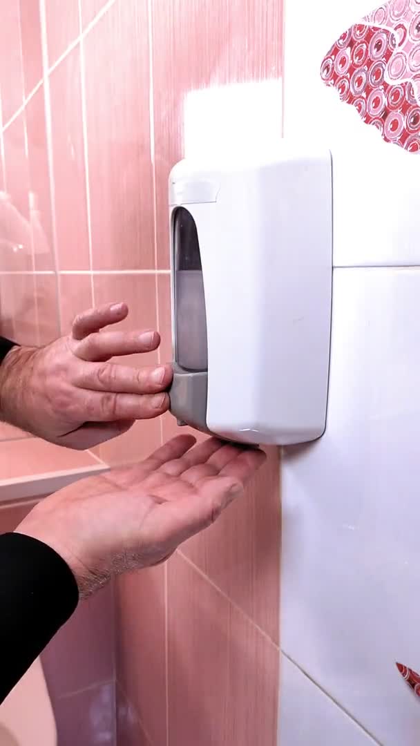 A man in a public place pours liquid soap on his hands. — Stock Video