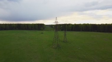 Yeşil bahar ormanı ve tarlasının her iki tarafında da daha uzun elektrik hatları var.