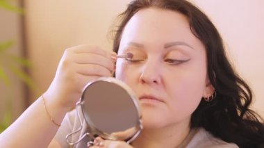 Genç bir kadın evinde aynanın önünde sonsuza dek parlak gölgeler bırakır..