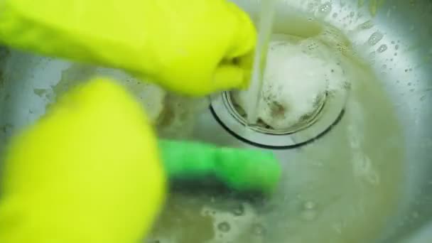 Eine Hand in einem Gummihandschuh wäscht Kalk und Rost mit einem Schwamm von der Oberfläche des Waschbeckens und spült es mit einem Wasserstrahl ab — Stockvideo