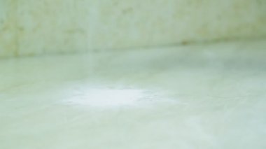 Masanın yüzeyine beyaz toz dökülüyor, eldivenli bir el toprağı süngerle ovuyor.