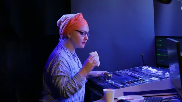 Une femme juive dans un foulard, un concepteur d'éclairage, programme la lumière pour un spectacle, parle à quelqu'un et boit du café. — Video