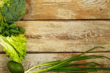 Yeşil sebzeler, brokoli, avokado, soğan, kabataslak bir masanın kenarındaki ıspanak..