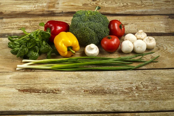 Verduras frescas de color brócoli, cebollas, tomates y pimientos, setas en la mesa de tablas ásperas . — Foto de Stock