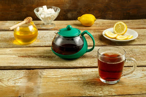 Kettle and cup with tea with lemon and sugar on the table. — Stock Photo, Image