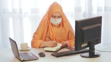 Ofiste hijdaba 'da çalışan Müslüman bir kadın bilgisayardaki bilgilerle çalışıyor. Genel plan