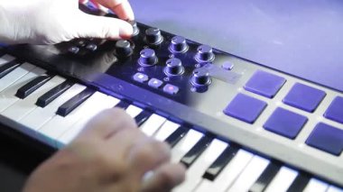 Kadın elleri midi klavyesinde çalar ve fader 'ı ayarlar. Ortalama plan