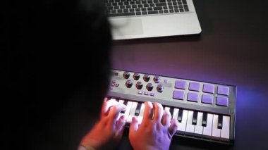 Kadın elleri midi klavyesinde çalar ve anahtarı seçer. Ortalama plan