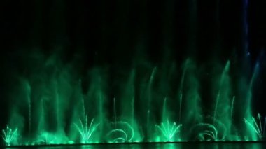 Farklı renklerde parlayan alışılmadık su bileşimleri gece gökyüzüne karşı gelen çeşmeleri gösteriyor. Genel plan