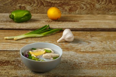 Limonlu soğan ve sarımsağın yanında ahşap bir masada tavuklu hafif bir tabak Vietnam Pho çorbası. Yatay fotoğraf