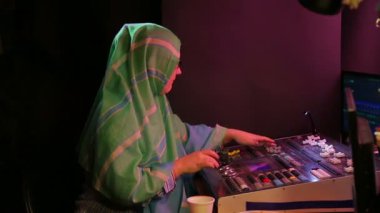 Işık tasarımcısı, tesettürlü ve gözlüklü Müslüman bir kadın ışığı programlar, kahve içer. Ortalama plan