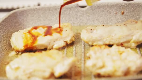 Filet de poulet dans une casserole à l'huile est versé avec de la sauce soja. Gros plan 