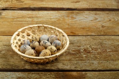 Tahta bir masada hasır sepetteki taze bıldırcın yumurtaları..
