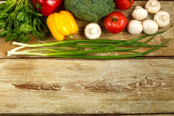 Verduras frescas de color brócoli, cebollas, tomates y pimientos, setas en la mesa de tablas ásperas . — Foto de Stock