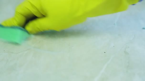 En hand i en gummihandske tvättar smuts med en svamp från bordsytan — Stockvideo