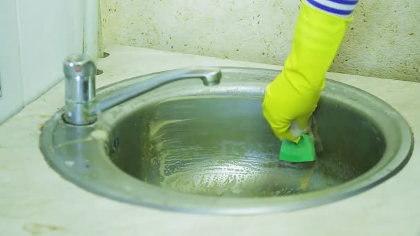 Seorang wanita dalam sarung tangan karet mencuci limescale dan karat dari permukaan wastafel dengan spons dan deterjen dengan busa. — Stok Video