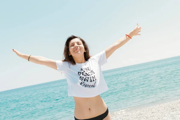 Relaxed woman enjoying sun, freedom and life on beautiful beach in sunshine. Concept of vacations.