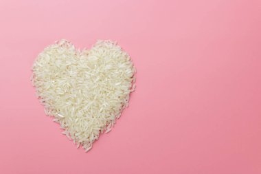 Pembe arka planda kalp şeklinde pirinç taneleri, Sevgililer Günü