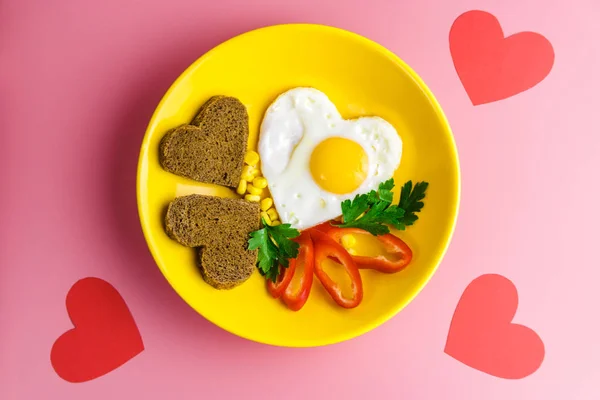 Valentines day breakfast. heart-shaped fried egg and bread in a yellow plate on a red background — Stock Photo, Image