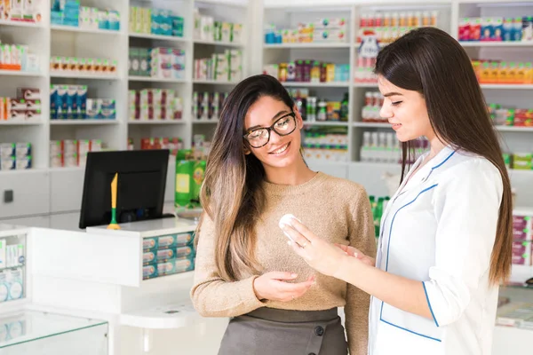 Memnun müşteri. Eczanede profesyonel danışmanlık. Kendine güvenen eczacı, eczanedeki bir ürün hakkında müşterisine danışıyor