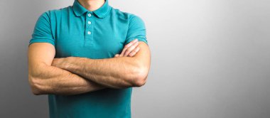 Güven ve güvenilirlik. Gri arka planda, fotokopi alanı olan bir adamın kolları kesişti.