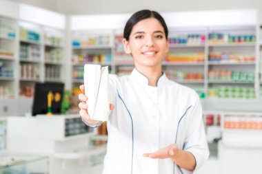 İki beyaz kavanoz tutan çekici bir eczacı. ürün reklamı