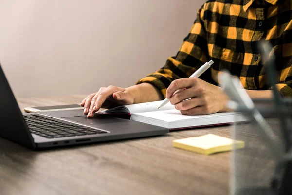 Fechar as mãos de uma mulher de negócios, estudante ou freelancer em camisa amarela fazendo anotações em seu caderno. o estudo é poder — Fotografia de Stock