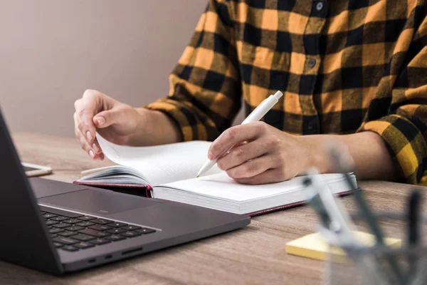 O estudo é poder. fechar as mãos de uma mulher de negócios, estudante ou freelancer em camisa amarela fazendo anotações em seu caderno — Fotografia de Stock