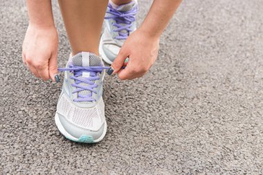 Kaçma zamanı. Ayakkabı bağcıklarını asfalta bağlayan kadının yakın plan görüntüsü