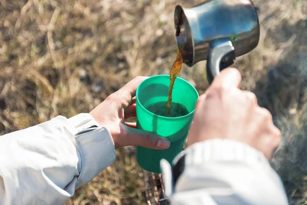 closeup hiker hands pouring coffee outdoors in mountains