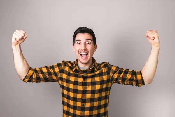 Winner. happy excited man in yellow shirt celebrating a winning gesturing with both arms — Stock Photo, Image
