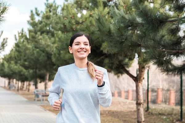 Egészséges életmód. vidám vonzó nő fut a parkban fenyőfák reggel — Stock Fotó