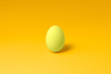 one pastel yellow color egg in center on yellow background easter concept design