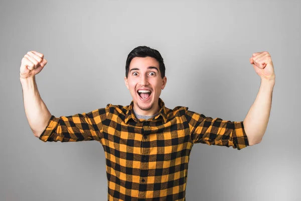 Happily excited handsome man with nice smile with both arms raised up on grey background. winner in life — Stock Photo, Image