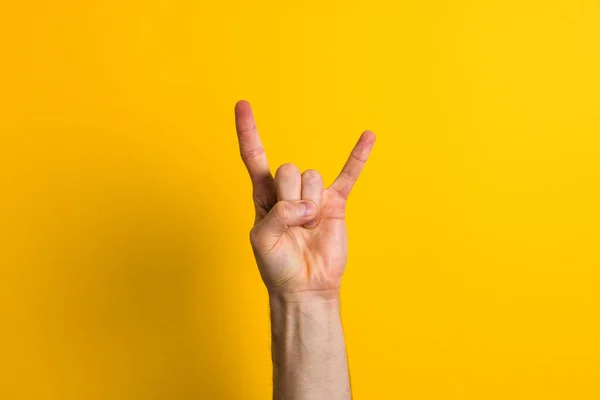 Primer plano mano masculina mostrando gesto de roca sobre fondo amarillo — Foto de Stock