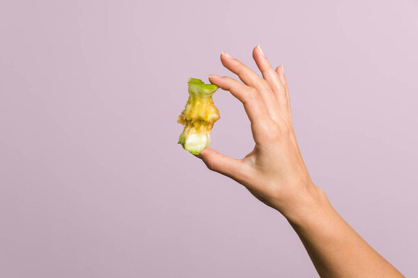close up tender female hand gently holding an apple core over pastel pink background. healthy food concept.