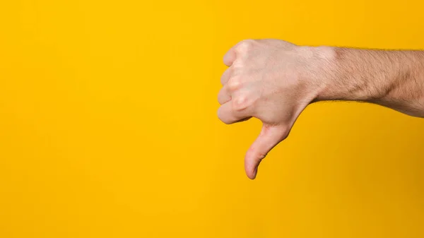 Není dobré a neschválené. zblízka nahoru ruka muže ukazující palec dolů nechutné znamení přes žluté pozadí s copyspace pro design — Stock fotografie