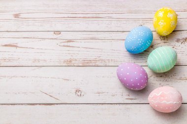 Paskalya arkaplanı elle boyanmış pastel renkler açık renkli ahşap masa üzerinde yumurtalar.