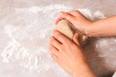 Evde sağlıklı ekmek pişirme süreci. Yakın plan kadın elleri parlak mutfakta mermer tezgahta çavdar unundan hamuru yoğuruyor..