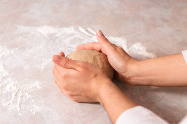 Evde sağlıklı ekmek pişirme süreci. Yakın plan kadın elleri parlak mutfakta mermer tezgahta çavdar unundan hamuru yoğuruyor..