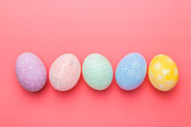 Çok renkli el boyaları ve pembe arka planda dekore edilmiş yumurtalar. Paskalya geleneği