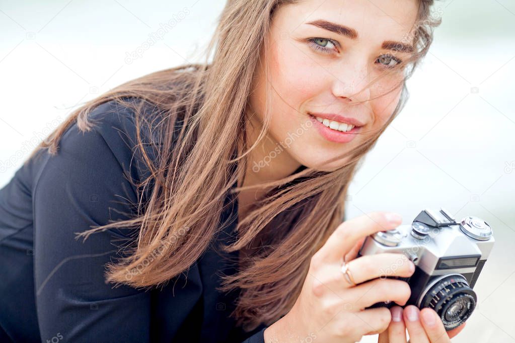 Beautiful young girl holding old film camera